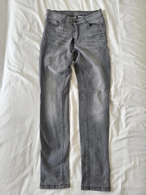 Upcycled / Remake Grå Jeans – Storlek 38,vinted  - Säljer ett par snygga grå jeans med den perfekta råa karaktären och en cool, ingången estetik.Skick: Jeansen har en maskinsydd lagning/förstärkning i grenen samt en dekorativ, tät lagning på benet som ger dem en helt rätt upcycled- och remake-look. Obs! Det finns inga öppna hål i jeansen. De är helt täta och bärbara🏷️ Bonus: Originaletiketten/papperslappen från butiken sitter fortfarande kvar på jeansen, vilket ger en extra cool retrodetalj för remake-stilen.Exakta mått (mätta platt):Midjemått: 3