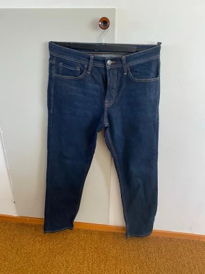 Mörkblå raka jeans från Produkt - Snygga mörkblå jeans från Produkt med klassisk femficksmodell och raka ben. Jeansen har kontrastsömmar och en patch med logga bak i midjan. Perfekta till vardagslooken och passar till det mesta. Tillverkade i slitstark denim.