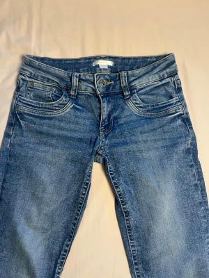 blåa lågmidjade utsvängda jeans - Blåa  jeans från gina tricot som är lågmidjade och utsvängda. De har inga slitna kanter men lite missfärgning på baksida höger lår men inget man tänker på. Passar XS & S men de är från gina young i storlek 164