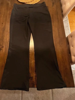 Svarta bootcut kostymbyxor från Nelly - Säljer ett par svarta kostymbyxor från Nelly med bootcut-modell. De har hög midja och är tillverkade i ett stretchigt material som sitter snyggt. Perfekta för dig som gillar en enkel men trendig look.