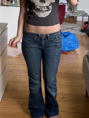 Mörkblå bootcut jeans med låg midja - Säljer ett par mörkblå bootcut jeans med låg midja och klassiska fem fickor. Jeansen har kontrastsömmar och en snygg tvättad look🙌🏼🤩W:28 och L:32, innerbens längden är 74cm❣️