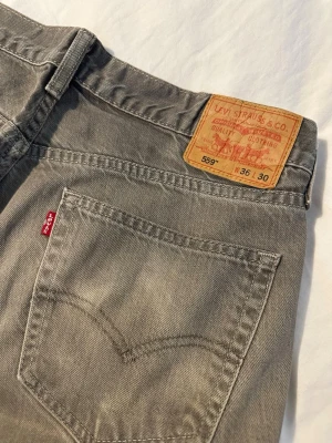 Grå Levi's 559 jeans straight fit - Säljer ett par grå Levi's 559 jeans med straight/baggy fit. Tillverkade i slitstarkt denimtyg, perfekta för en avslappnad och cool stil. Jag skulle personligen säga att storleken är 34/32 snarare än vad som står på byxorna.