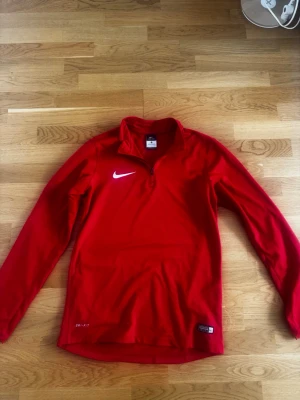 Nike dri-fit zip - Nike Dri-FIT Half-Zip Träningströja – Röd  Säljer en snygg och funktionell Nike Dri-FIT träningströja i stark röd färg. Perfekt för löpning, gym, fotboll eller annan träning. Tröjan är tillverkad i Nikes Dri-FIT-material som effektivt transporterar bort fukt och hjälper dig att hålla dig torr och bekväm under aktivitet.  Produktinformation  * Märke: Nike * Modell: Dri-FIT Half-Zip / Quarter-Zip * Färg: Röd * Storlek: S men passar M * Material: Funktionsmaterial (Dri-FIT) * Långärmad * Kort dragk
