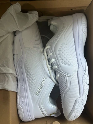 Vita sneakers från Salming - Fräscha helt oanvända helvita sneakers från Salming med sportig design och detaljerad textur på sidorna. Skorna har lågt skaft, snörning och slitstark sula. Perfekta för dig som gillar en clean och stilren look. Materialet är en mix av syntet och mesh för bra andningsförmåga.
