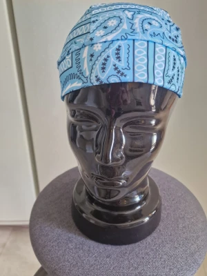 Bandanas ljusblå - Bandana pirathatt.  Stretchig snabbtorkande andningsbar och  vindtät. 55-60 cm huvud.