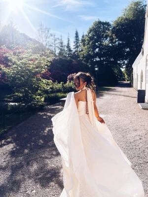 Champagnefärgad långklänning med snörning - Elegant långklänning från Miss rosier i champagnefärg med omlott och snörning i ryggen. Klänningen har ett axelbandslöst snitt med draperad tygdetalj över ena axeln och ett luftigt, svepande fall. Perfekt för sommarens speciella tillfällen. Storlek xs nypris 2500kr