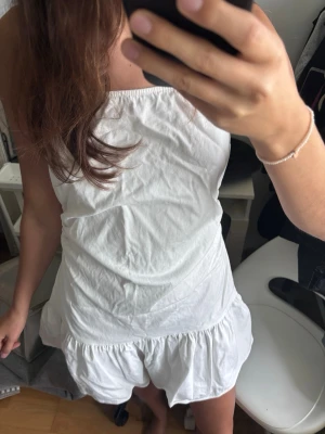 Vit klänning  - Supersöt vit jumpsuit med volangkant nertill och tunna axelband. Den är ärmlös och har en luftig passform, perfekt för varma dagar. Aldirg använt 