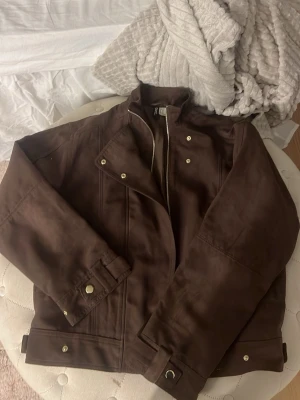 Brun mockajacka  - Snygg brun mockajacka med guldiga knappar. Jackan har en klassisk bikerstil med markerad krage och justerbara spännen vid ärmslut och midja. Storleken är xs men den är lite större så den är som storlek s🩷