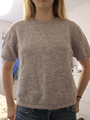 Ljusgrå stickad t-shirt - Mysig ljusgrå stickad t-shirt med rund hals och korta ärmar. Perfekt till jeans eller kjol för en avslappnad men ändå stilren look. Mjuk och skön mot huden. Pris kan diskuteras 🫶