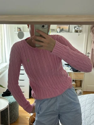 Rosa kabelstickad tröja Ralph Lauren - Säljer en rosa kabelstickad tröja från Ralph Lauren med rund halsringning och lång ärm. Tröjan har det klassiska gröna Polo-logot på bröstet. En slim modell. 