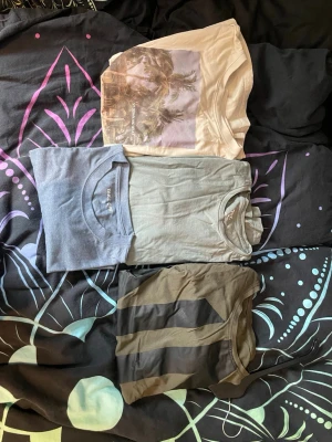 4-pack t-shirts i olika färger - Säljer fyra t-shirts i olika färger och stilar. En beige t-shirt med palmtryck, en ljusgrå t-shirt och en mörkgrå t-shirt med svarta ränder. Alla har rund hals och korta ärmar, perfekta för en avslappnad look. Alla är i storlek S. Priset är inte huggit i sten och kan diskuteras.