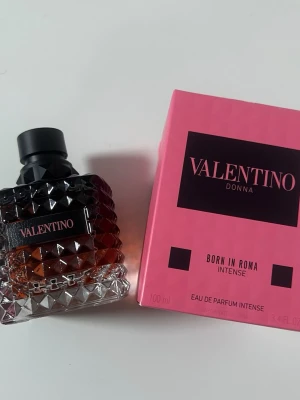 Valentino Donna Born In Roma Intense EdP - Valentino Donna Born In Roma Intense Eau de Parfum i 100 ml flaska. Flaskan är elegant med nitar och svart kork, och doften kommer i en snygg rosa och svart förpackning. Perfekt för dig som gillar lyxiga och intensiva parfymer.