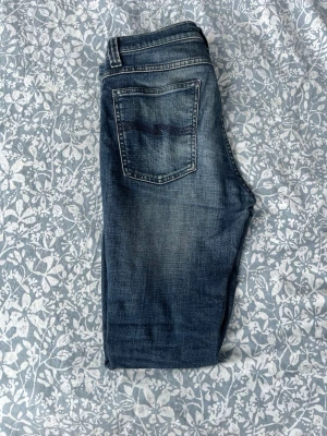 Mörkblå slim fit jeans - Snygga mörkblå slim fit jeans med lätt slitna detaljer och klassisk femficksmodell. Jeansen har normal midja och smala ben, perfekta till en avslappnad stil. Materialet är denim i bomull med lite stretch för extra komfort.