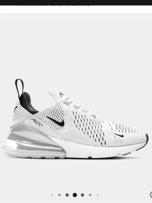 Nike Air Max 270 vita sneakers - Nike Air Max 270 sneakers i vitt med svarta detaljer och stor synlig Air-enhet i hälen. Ovandelen är i mesh för bra ventilation och har en modern, sportig look med tydliga loggor. Skorna har lågt skaft och en chunky sula som ger extra komfort.