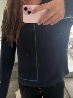Mörkblå stickad tröja från Zara - Mysig mörkblå stickad tröja från Zara med en unik ljusblå söm som går längs framsidan och ner mot nederkanten. Tröjan har rund halsringning och långa ärmar. Perfekt för lager-på-lager och chill dagar.
