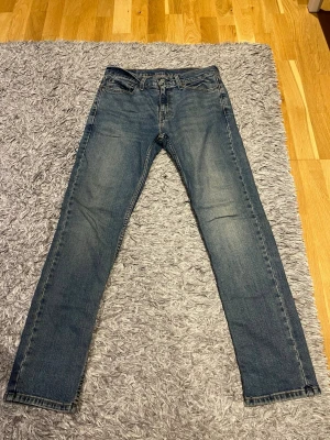 Blå Levi's skinny jeans - Säljer ett par klassiska blå skinny jeans från Levi's med fem fickor och dragkedja. Jeansen har en snygg tvätt med lätt slitning och raka ben. Perfekta till en avslappnad stil och passar till det mesta i garderoben.