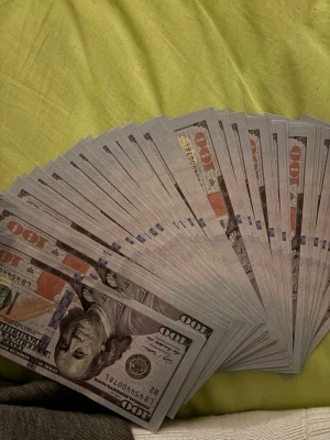 Falska 100-dollar sedlar i bunt - Säljer en bunt med falska 100-dollar sedlar, perfekta som rekvisita till film, foto eller dekoration. Sedlarna har tryck i blått, orange och grått och är tillverkade i papper. De ser ut som amerikanska dollarsedlar men är inte giltiga som betalningsmedel.