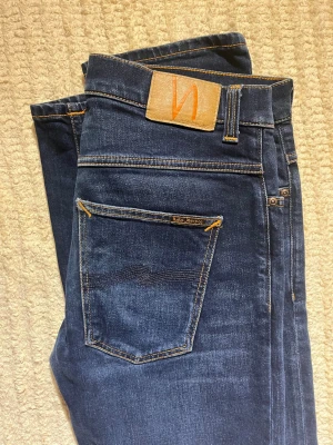 Mörkblå jeans från Nudie Jeans - Snygga mörkblå jeans från Nudie Jeans med klassisk femficksmodell och slimade ben. Modellen är grim trim. W33:32! Priset kan diskuteras!