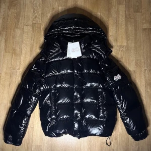 Moncler jacka svart - Svart Moncler jacka i ny skick förutom att där man justerar är syd ihop men inget som syns, den har NFC i loggan, storleken är 4 som motsvarar L, pm vid frågor eller detaljbilder och kom gärna med prisförslag.