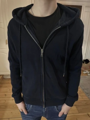 Mörkblå zip hoodie från Reserved - Säljer en mörkblå hoodie från Reserved med dragkedja framtill och justerbar huva med snören. Klassisk passform med ribbade muddar vid ärmar och nederkant. Perfekt till jeans eller joggers för en avslappnad look.