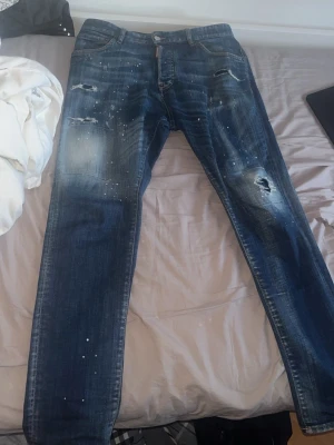  Äkta  DSQUARED2 jeans  - Säljer ett par blå jeans från DSQUARED2 med slitningar, hål och färgstänk. Helt äkta och fräscha. Använda ett par gånger 