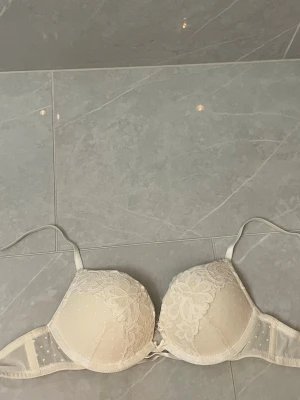 Vit push-up bh med spetsdetaljer Hunkemöller  - Säljer en vit push-up bh med vadderade kupor och fina spetsdetaljer upptill. Bh:n har justerbara axelband. Helt oanvänd! 