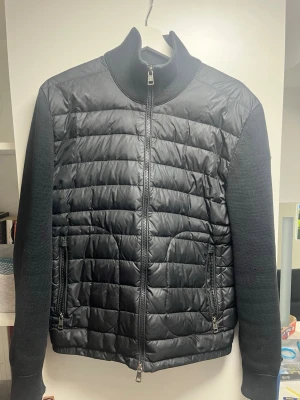 Moncler cardigan - Säljer denna svarta Moncler cardigan i storlek L, (fits M). Fint skick, se små flaws vid ärmarna annars otroligt fin.