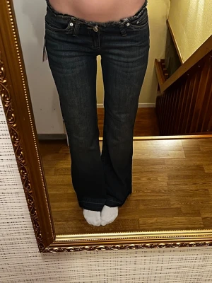 Nya populära lågmidjade jeans - Helt nya trendiga mörkblå lowwaist utsvängda jeans från Nelly i storlek 34 short. Modellen heter No Waist Bootcut Jeans 
