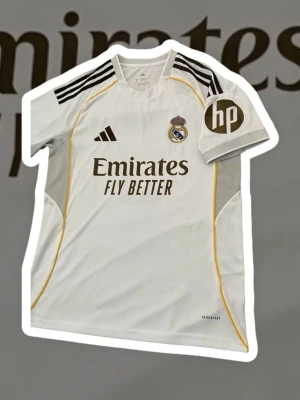 Real Madrid Bellingham matchtröja - Säljer min Real Madrid hemmatröja från säsongen 2023/2024 med Bellingham #5 på ryggen. Riktigt snygg klassisk vit design med fina gulddetaljer. Tröjan är från Adidas och sitter bra med slim fit-passform.  Storlek: M  Passform: Slim fit  Skick: Väldigt bra, sparsamt använd  Material: Aeroready – bekväm och luftig  Originaldetaljer: Klubblogga, sponsortryck och namn/nummer i fint skick  Perfekt både att bära till match, träning eller till vardags om du är Real-fan. Säljer den då den inte kommer ti