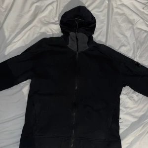 CP Company Zipper - Zipper ifrån cp company. Den har en tajt huva och det klassiska CP company märket på armen. Den är i bra skick. Säljes pga används ej. storlek XL men passar M