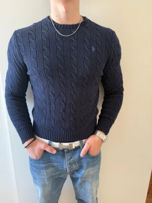 Mörkblå kabelstickad tröja Polo Ralph Lauren - Säljer en mörkblå kabelstickad tröja från Polo Ralph Lauren.Perfekt för en stilren och klassisk look. Storlek M i bra skick