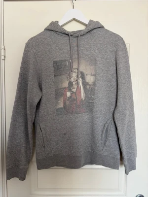 Grå hoodie med tryck  - Säljer min riktigt snygga Marilyn Monroe hoodie som jag fått många komplimanger för men som nu är för liten. Finns inte längre att köpa, nypris 900kr och jag säljer nu för 350kr!!  Den är i fint skick.