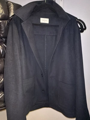 Mörkblå  ullkappa från Brothers - Stilren svart kappa från Brothers i storlek S. Klassisk rak modell, ett mjukt ullmaterial som håller dig varm under kyliga dagar. Helt nytt skick använt en gång!