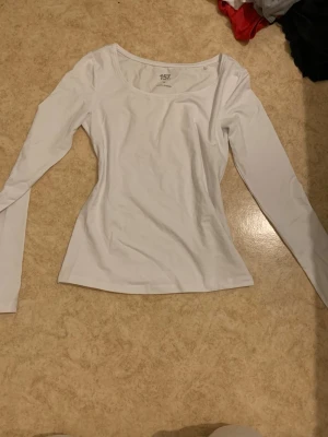 Vit långärmad topp - En enkel och stilren vit långärmad topp med rundad halsringning. Tillverkad i mjuk bomull som sitter skönt mot kroppen. Perfekt att matcha med jeans eller kjol för en clean look.