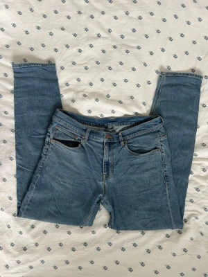 Blå raka jeans med fickor ASOS - Säljer ett par klassiska blå jeans med rak passform och fickor från ASOS. Jeansen har normal midja, bälteshällor och stängs med dragkedja och knapp. Materialet är slitstark denim i 100% bomull. Perfekta till vardagslooken! W34 L34. Waist 34. 