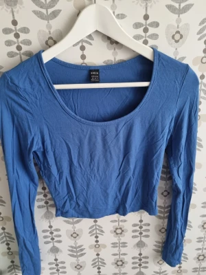 Blå croppad långärmad topp SHEIN - Säljer en blå croppad topp från SHEIN med lång ärm och rund halsringning. Toppen är enkel och stilren, perfekt att matcha med höga jeans eller kjol. Materialet känns mjukt och stretchigt.