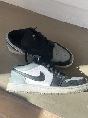 Air Jordan 1 Low svart/grå - Säljer ett par Air Jordan 1 Low i svart, grått och vitt läder. Klassisk siluett med svart swoosh, svart snörning och Jumpman-logga på plösen. 