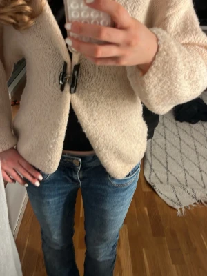 Beige stickad kofta - Mysig beige stickad kofta. Koftan har en avslappnad passform, långa ärmar och är gjord i ett mjukt material som känns skönt mot huden. Perfekt att slänga över en topp för en chill look.