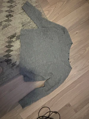 Grå stickad tröja med rund hals - Mysig grå stickad tröja med rund hals och långa ärmar. Tröjan har en enkel och stilren design som passar perfekt till jeans eller kjol. 