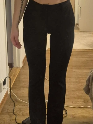 Svarta kostymbyxor med stretch - Snygga svarta kostymbyxor med rak passform och lätt utsvängda ben. Byxorna är tillverkade i ett mjukt, stretchigt material. Perfekta för en clean och stilren look. Storlek xs, längd 30.