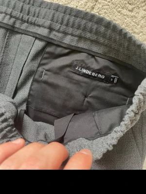 Mörkgrå kostymbyxor  - Snygga mörkgrå kostymbyxor med rak passform och resår i midjan samt dragsko. Byxorna har pressveck framtill och två bakfickor med knapp. Perfekta för en clean och stilren look. Pris kan diskuteras 