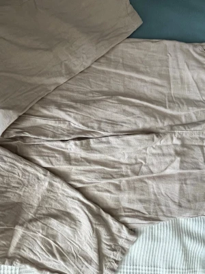 Beige linnebyxor med dragsko - Säljer ett par beige linnebyxor med avslappnad passform och bred resår i midjan. Byxorna har en justerbar dragsko och är tillverkade i ett luftigt linnetyg som känns perfekt för varma dagar. Inga synliga loggor eller märken.