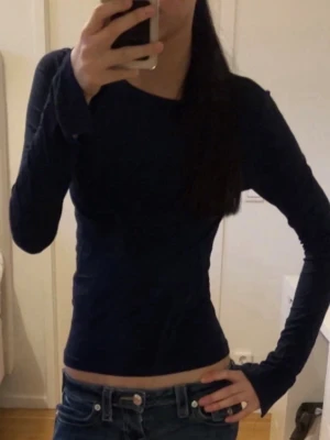 Svart långärmad topp - En enkel svart långärmad topp med rund halsringning. Modellen är tight och har en klassisk, stilren look som passar till det mesta. Perfekt basplagg i garderoben.