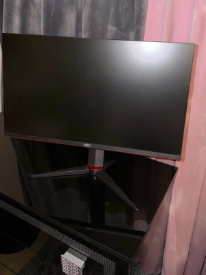 AOC gaming skärm 24 tum - Säljer en AOC gaming skärm med 24 tums display. Skärmen är svart med röda detaljer och har en modern, kantig design. Stativet är robust och justerbart. Perfekt för gaming eller arbete vid datorn. Materialet är plast och metall. Köpt för 3499kr