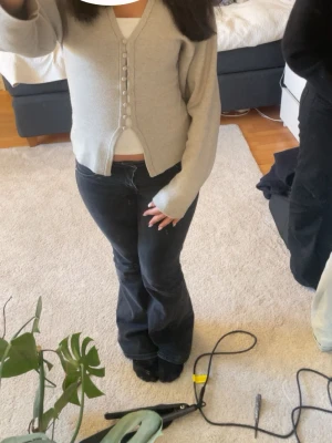 Beige tröja med knappar - Snygg beige tröja med v-ringning och dekorativa knappar framtill. Perfekt att bära över ett linne eller t-shirt om man vill täcka.