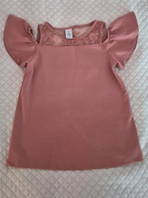 Söt blus barnstorlek Lindex - Gulligt linne med spets och volangärmar. Delvis off-shoulder💘 Storlek 134/140. Perfekt för mer uppklädda tillfällen. Har tyvärr inte kommit till användning.