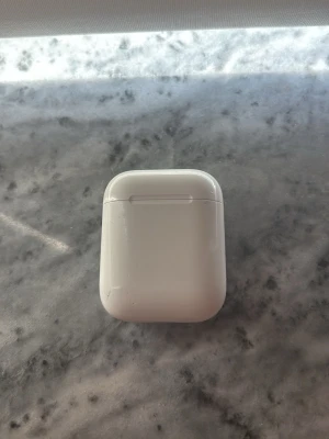 Apple AirPods med laddningsetui - Trådlösa vita Apple AirPods med matchande laddningsetui. Snygg och kompakt design i blank plast som är enkel att ta med sig. Perfekta för musik, poddar och samtal med smidig anslutning till iPhone och andra Apple-enheter. Laddare ingår (: 