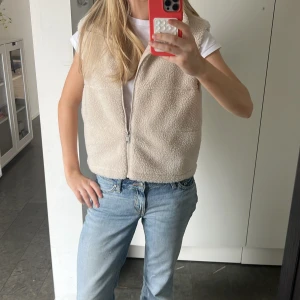 Beige teddyväst med dragkedja  - Mysig beige teddyväst med dragkedja framtill ⭐️Är lite liten i storleken och har därför i storlek M❣️ Perfekt att slänga över en t-shirt för en chill och trendig look😊 Pris kan diskuteras 