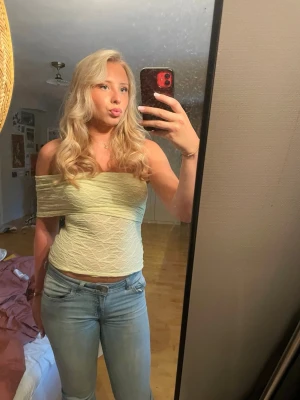 Ljusgul offshoulder spetstopp - Trendig ljusgul offshoulder tubtopp i ett tunt, lätt transparent material med vågig struktur. Toppen är axelbandslös och croppad, perfekt för varma dagar. Snygg att styla med jeans eller kjol för en cool look. Bara använt 1 gång.