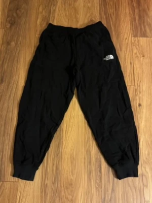 Svarta mjukisbyxor från The North Face - Säljer ett par svarta mjukisbyxor från The North Face med resår i midjan och muddar vid bensluten. Byxorna har en avslappnad passform och logga på vänster lår. Perfekta för chill dagar eller när du vill vara bekväm. Finns ett par likadana i grå, man kan köpa ett par för 75kr eller båda för 130kr!